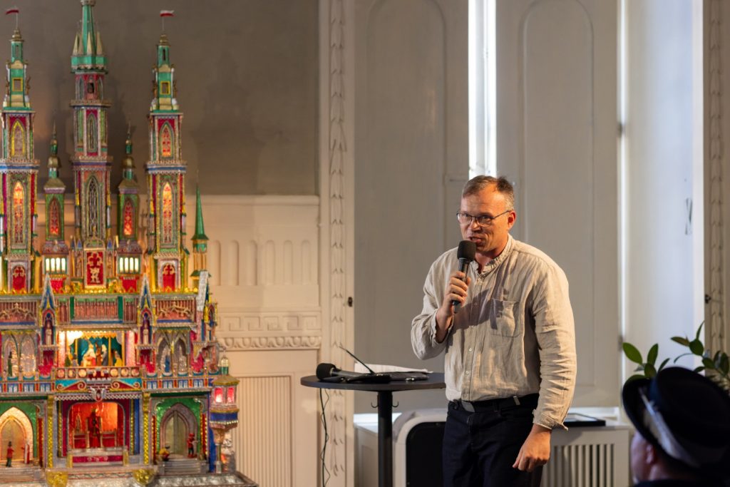 Prelegent podczas konferencji „Dziedzictwo, które żyje” na tle szopki krakowskiej